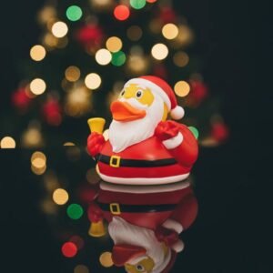 Santa Claus-themed rubber duck with a red suit, white beard, and bell, set against a festive bokeh background.