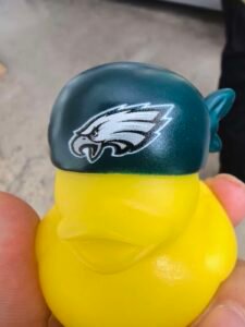 Close-up of a yellow custom rubber duck wearing a green cap with detailed UV-printed artwork