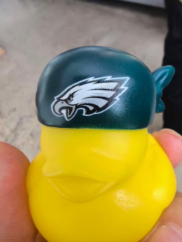 Close-up of a yellow custom rubber duck wearing a green cap with detailed UV-printed artwork